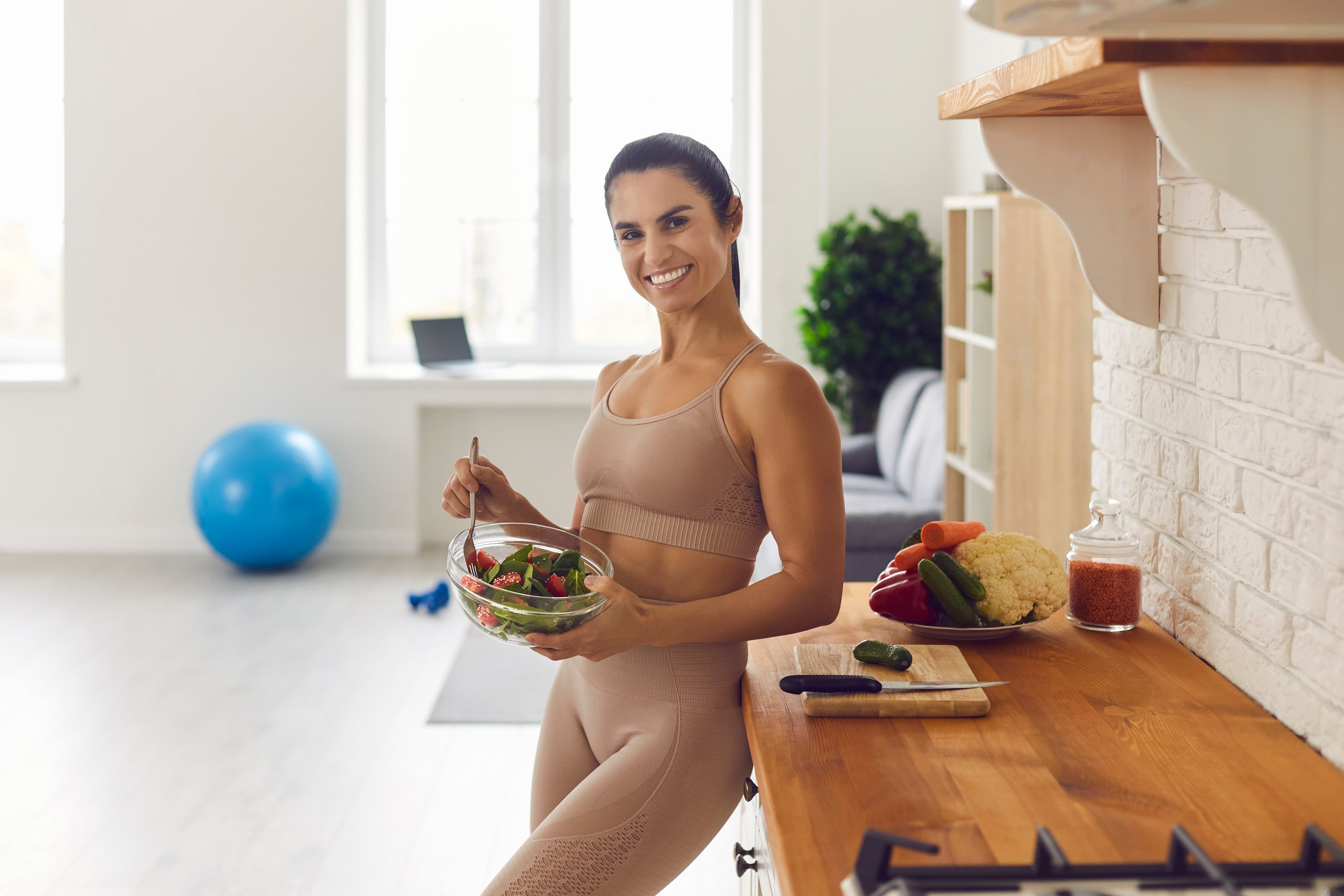 Happy Athletic Woman Eating Healthy Vegetable Salad after Fitness Workout at Home